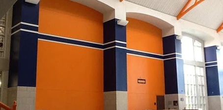 Commercial interior painting—large orange and blue painted walls inside a bright open facility.